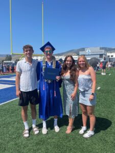 Gracie standing with her sister and two brothers at a graduation ceremony.