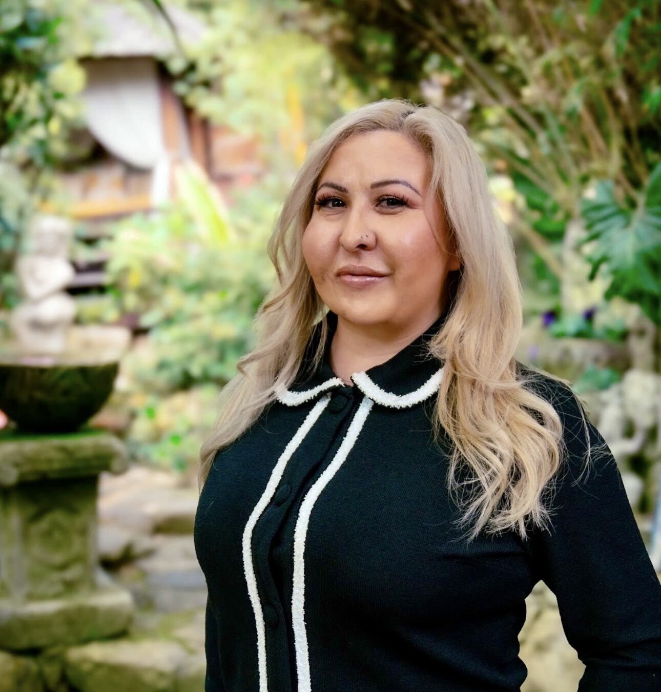 Vanessa looks at the camera in front of a nature background.