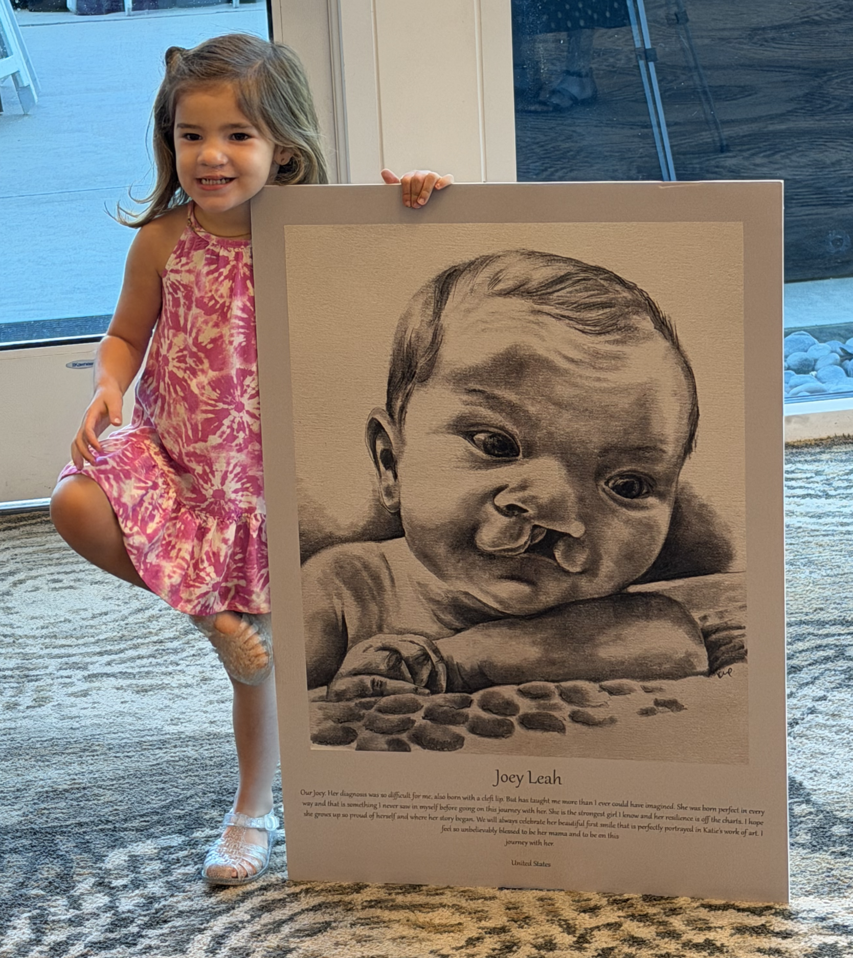 A child stands next to a portrait of herself as a baby.