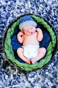Newborn baby sleeping inside a green wreath