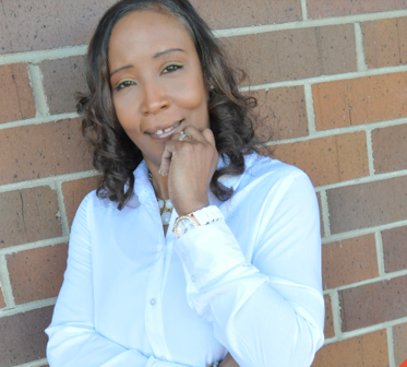 Smiling woman standing by a brick wall