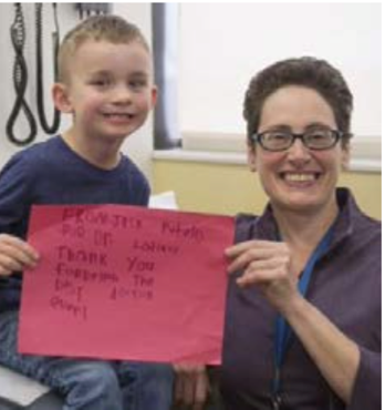 Boy and a cleft team member holding a sign