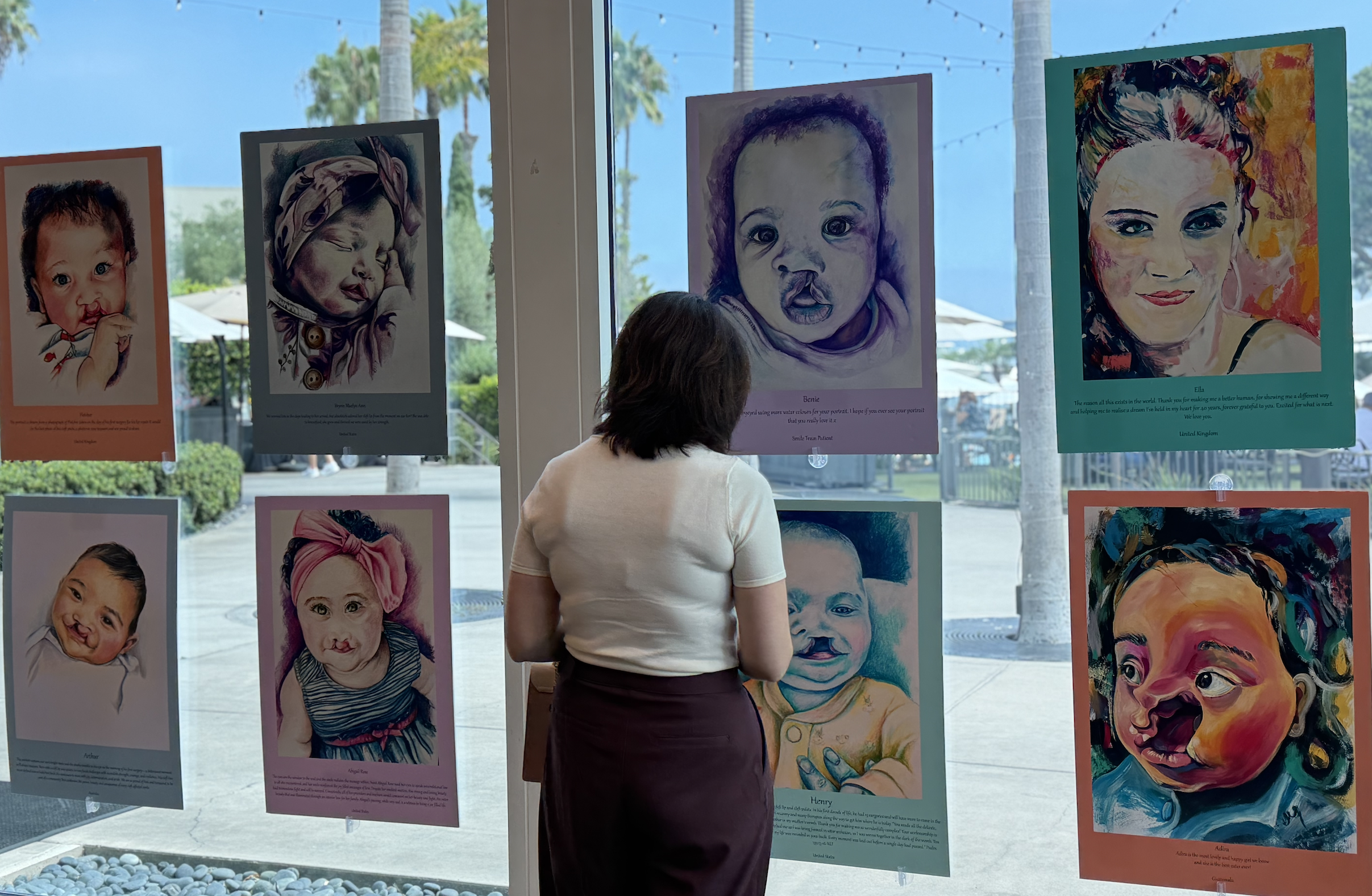 A woman looks at portraits hung on windows in San Diego, California